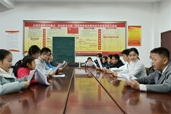 3889aa2ac9e842f2a8b46fea94a7aaad.jpg 图为志愿者带领社区学生学习红色文字(1)_edit_185330294307656.jpg